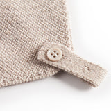 Nærbillede af knaplukning på beige strikket babyhue