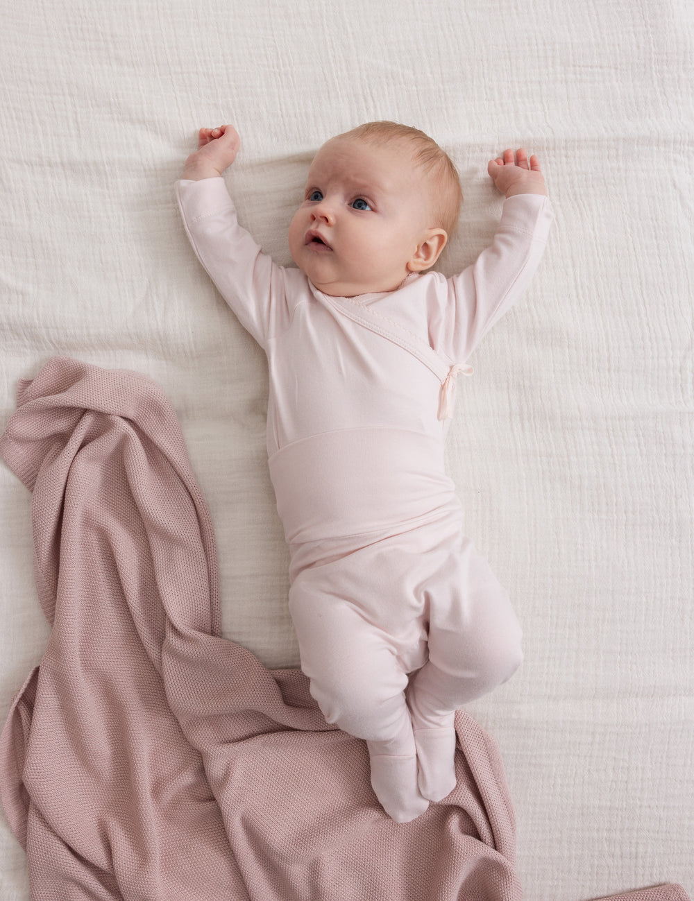 Barn med lyserød strikket babytæppe