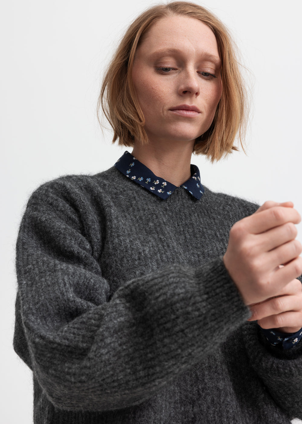 Kvinde iført mørkegrå strikbluse med afslappet pasform