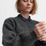 Kvinde iført mørkegrå strikbluse med afslappet pasform