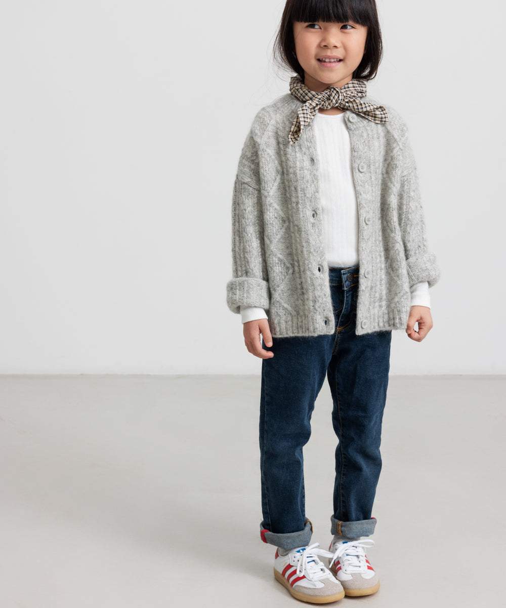 Pige iført hvid pointelle bluse og grå cardigan