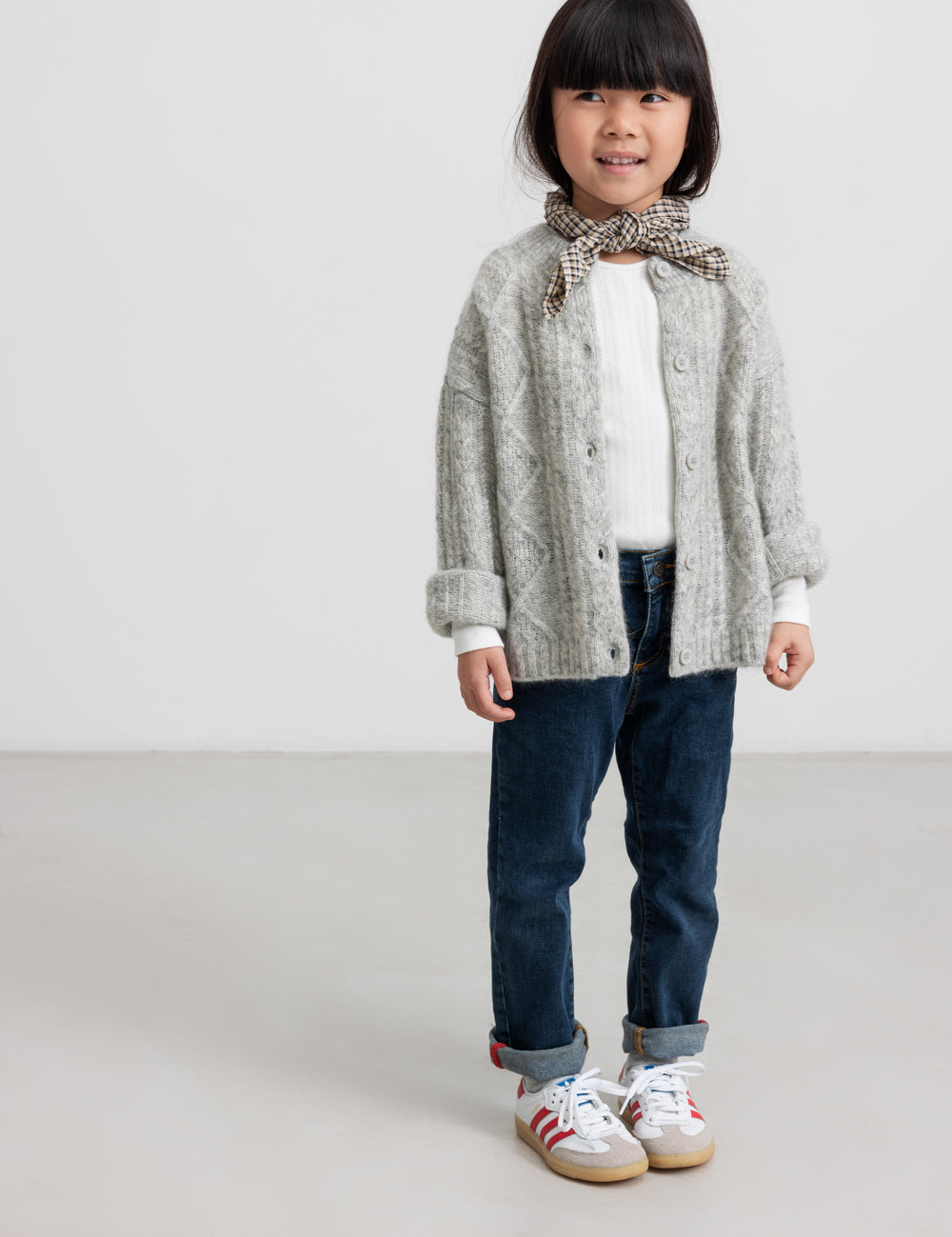 Pige iført hvid pointelle bluse og grå cardigan