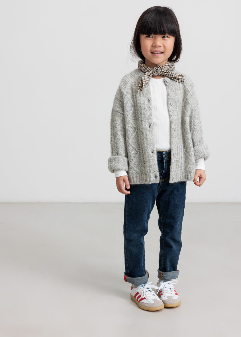 Børn iført lysegrå cardigan og jeans