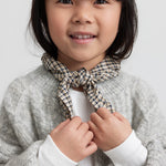 Pige med brun ternet tørklæde bundet om halsen