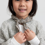 Pige iført lysegrå cardigan med ternet tørklæde