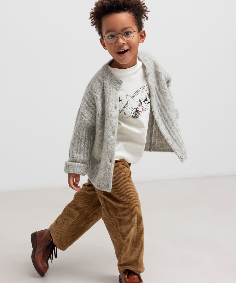 Dreng iført lysegrå cardigan og brune bukser