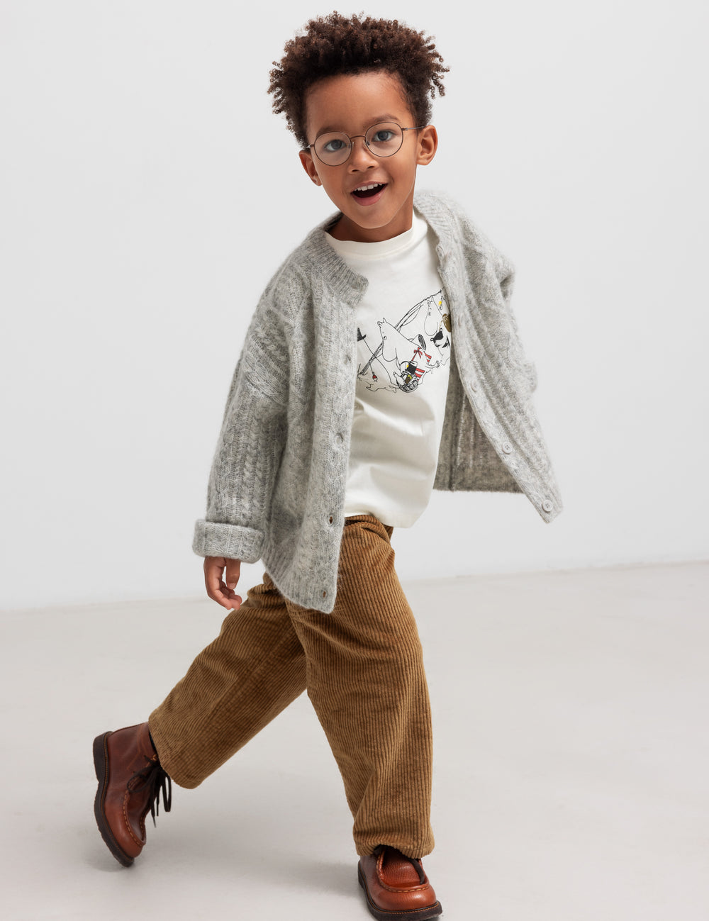 Dreng iført lysegrå cardigan og brune bukser