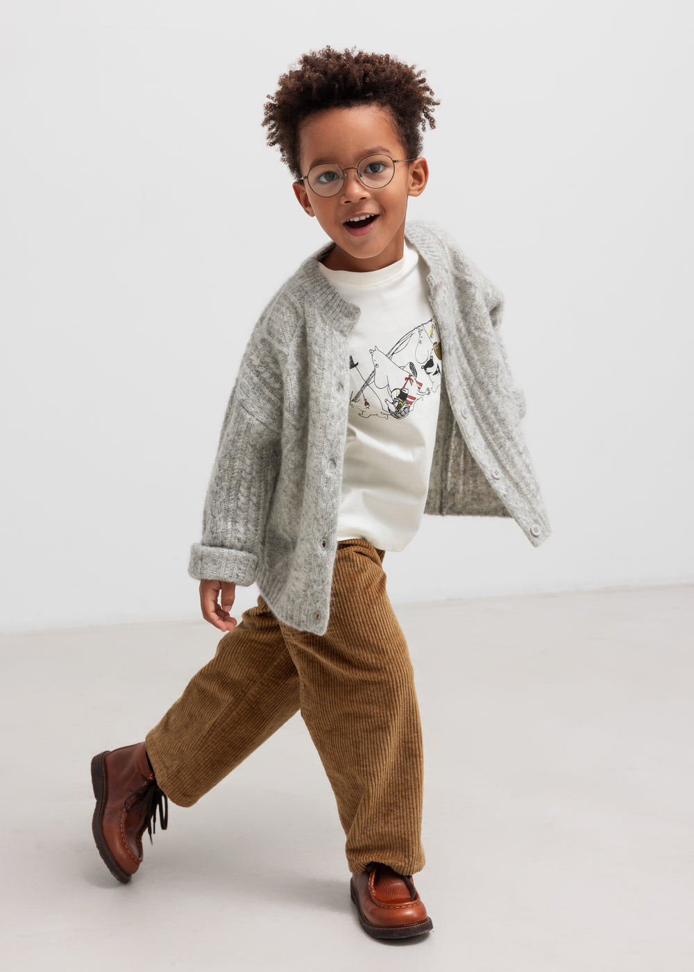 Dreng iført lysegrå cardigan og brune bukser