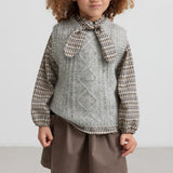 Børn iført kaki nederdel og strikvest set forfra