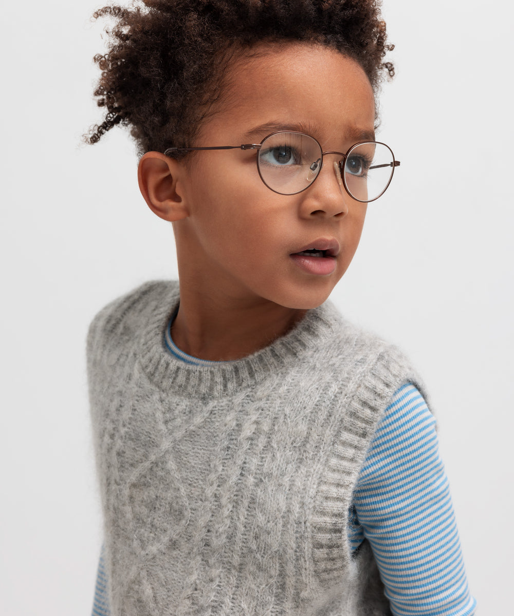 Dreng iført blå og hvid stribet bluse under grå strikvest