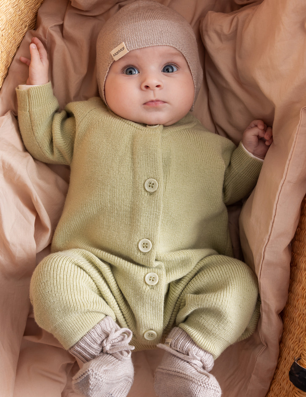 Baby wearing soft beige knitted jumpsuit with buttons at front