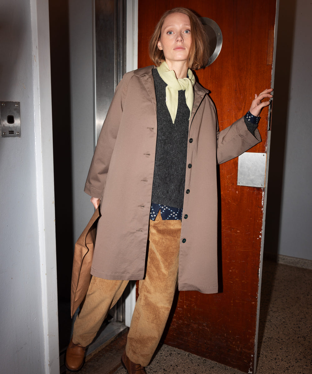 Kvinde iført kaki chino frakke, der åbner dør