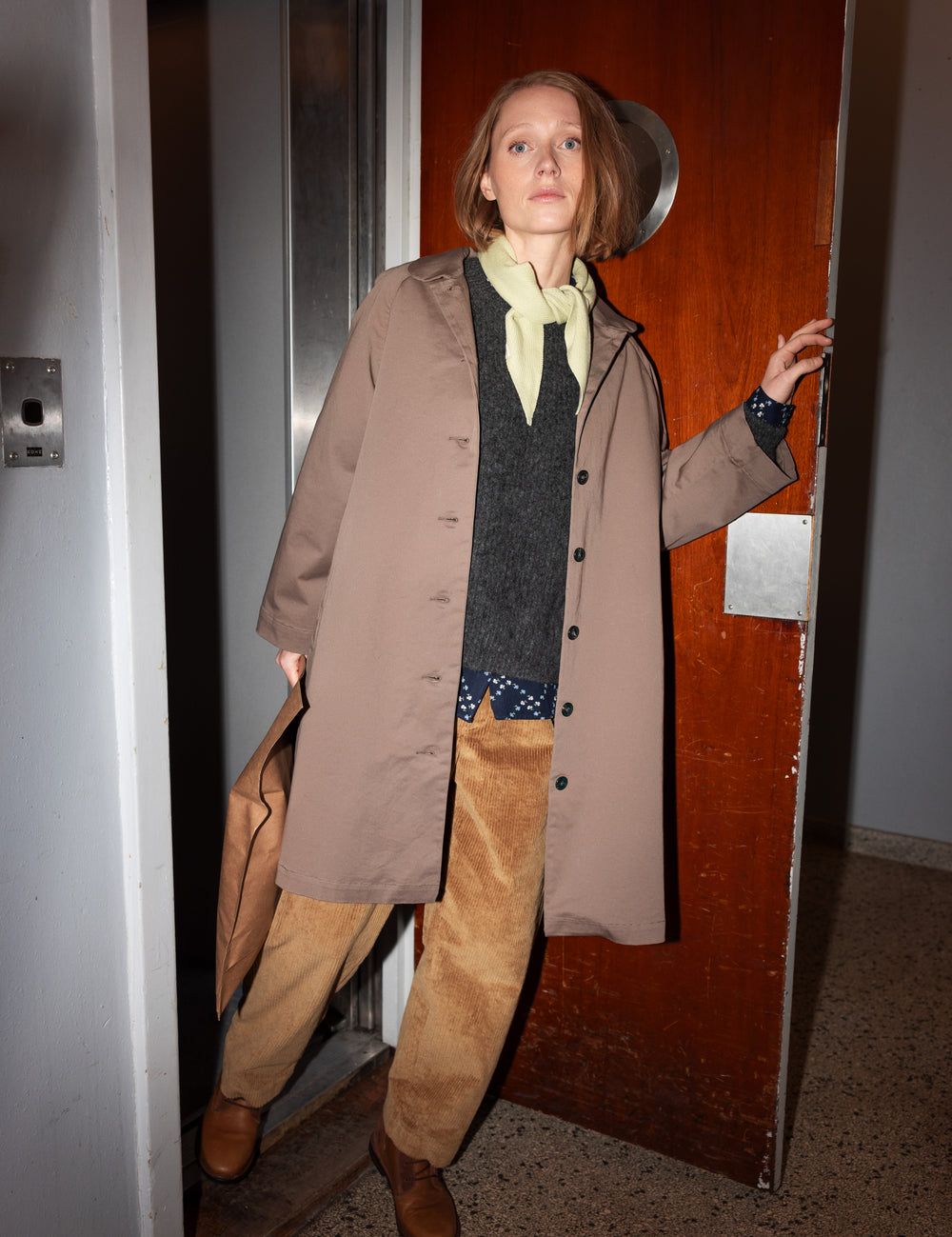 Kvinde iført kaki chino frakke, der åbner dør