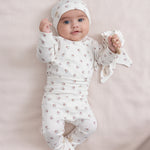 Baby iført blødt babytøj og futter liggende på ryggen