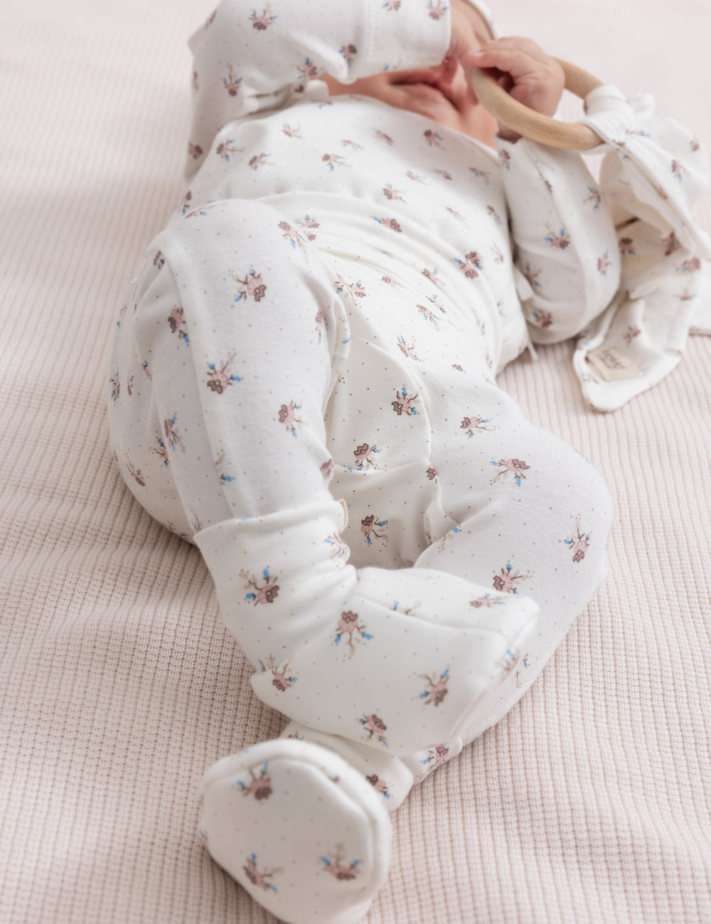 Baby iført blødt babytøj og ligger på ryggen.