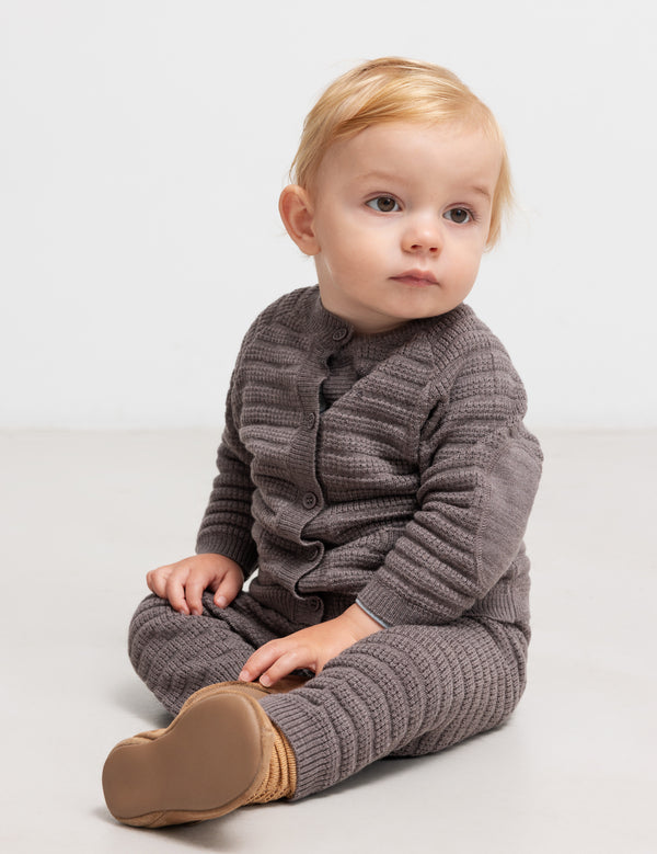 Baby i brun strikket cardigan og bukser med strukturmønster