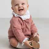 baby iført rosa strikket sæt med hvid flæsekrave