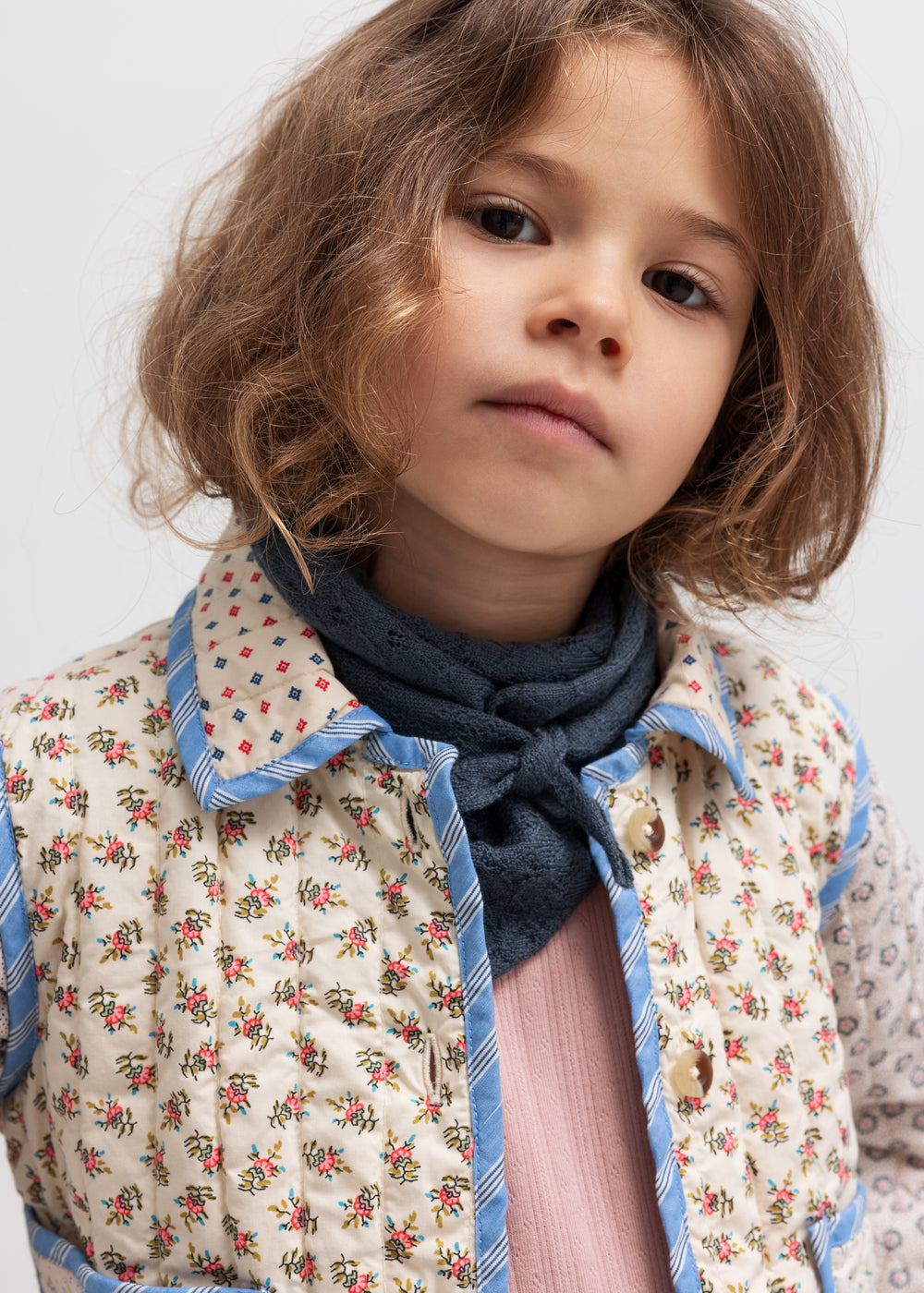 Pige iført rosa pointelle bluse, jakke og tørklæde