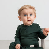 Baby iført mørkegrøn ribbet body med stolpeknapper