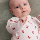 Baby iført cremefarvet slå-om bluse med rødt juleklokkeprint