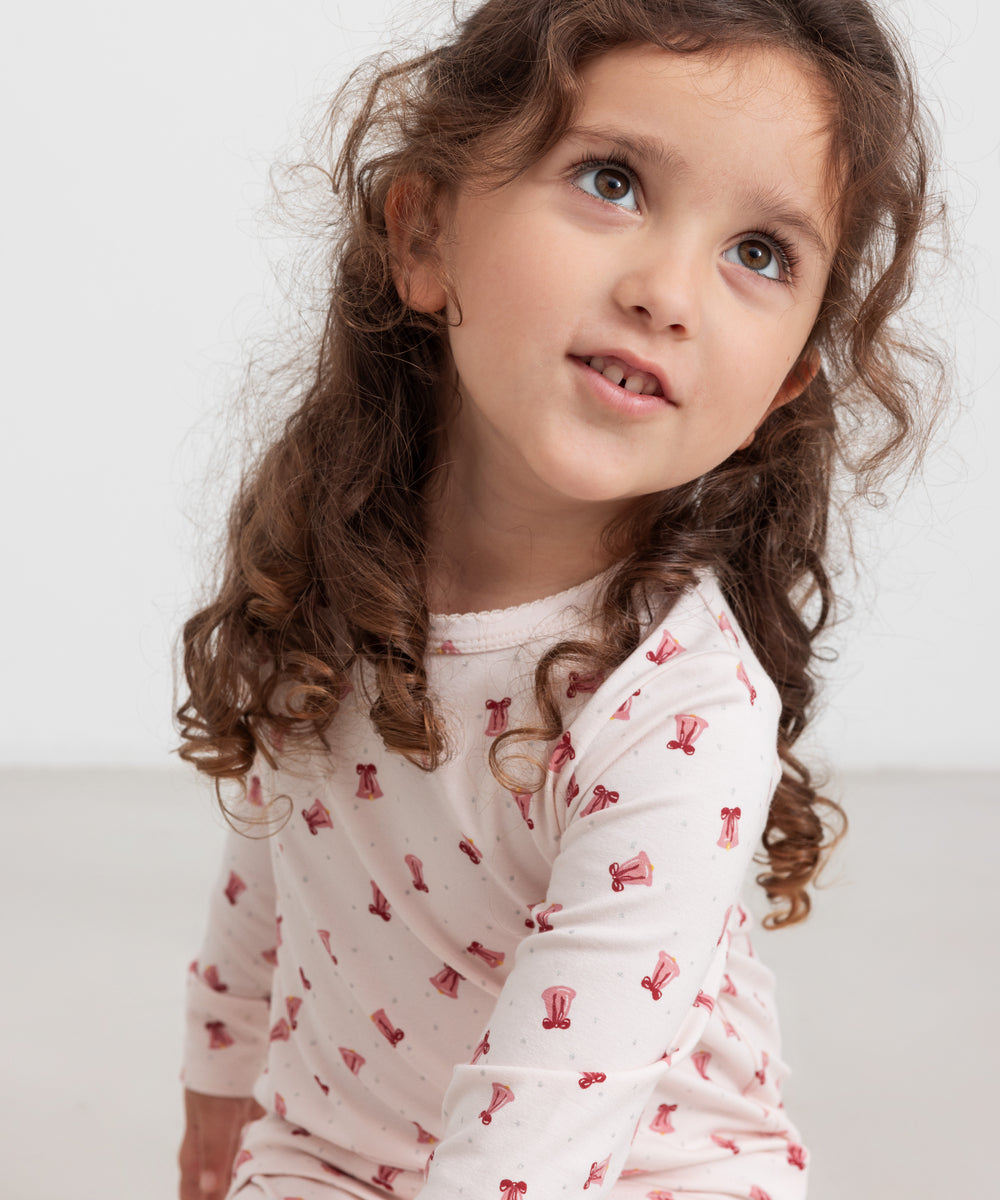 Børn iført cremefarvet julepyjamas med røde juleklokker