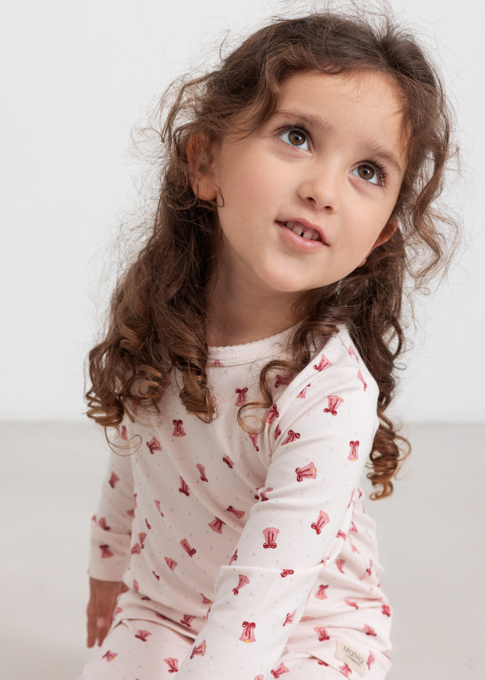 Børn iført cremefarvet julepyjamas med røde juleklokker