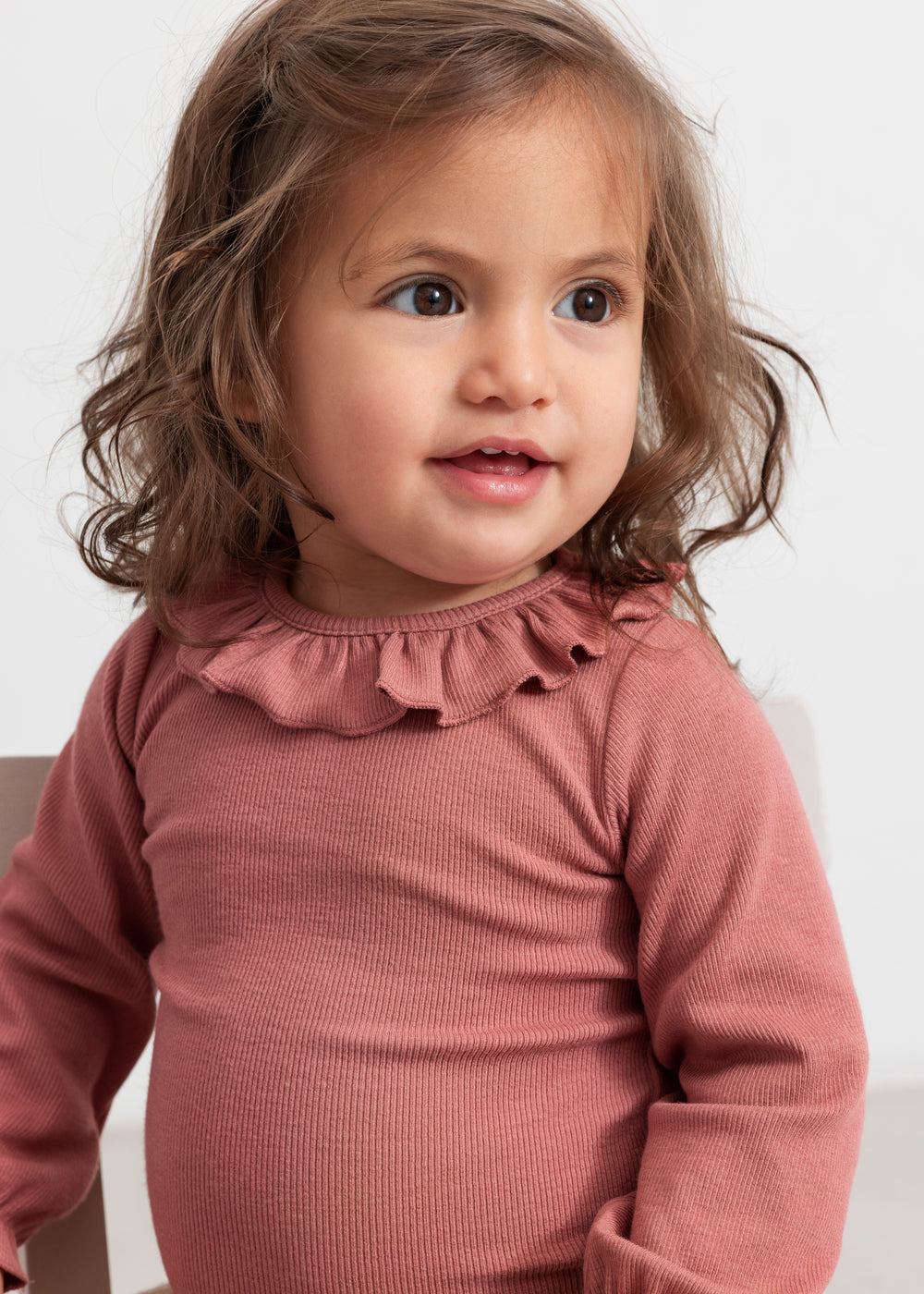 Baby iført støvet rosa body med flæsekrave