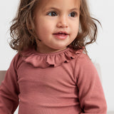 Baby iført støvet rosa body med flæsekrave