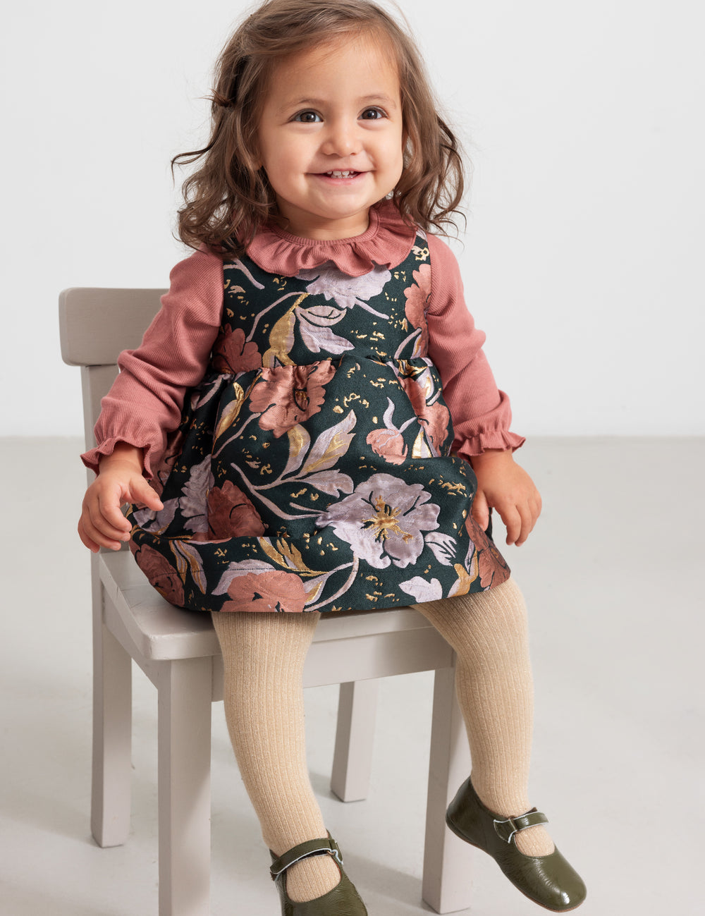 Baby wearing dusty pink bodysuit and floral print dress