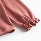 Detalje af ærmekant med små flæser på støvet rosa bluse til børn