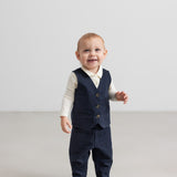 Baby iført mørkeblå vest, skjorte og bukser i festligt juletøj til baby