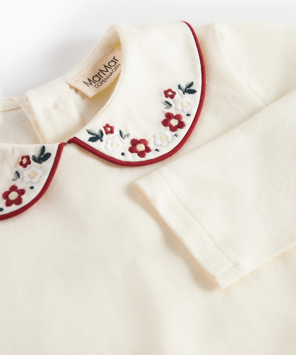 Hvid bodystocking med krave og fine blomsterbroderier til baby