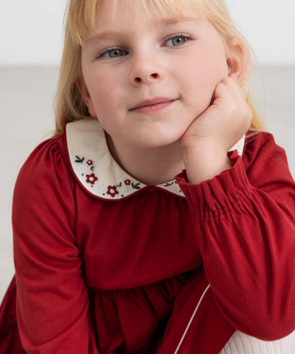 Pige iført rød julekjole med broderet krave i elegant festlook til børn