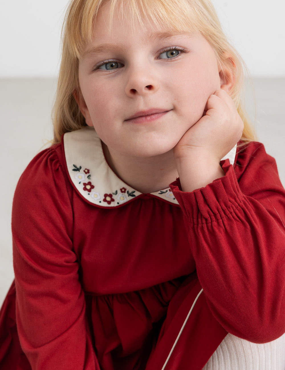 Pige iført rød julekjole med broderet krave i elegant festlook til børn