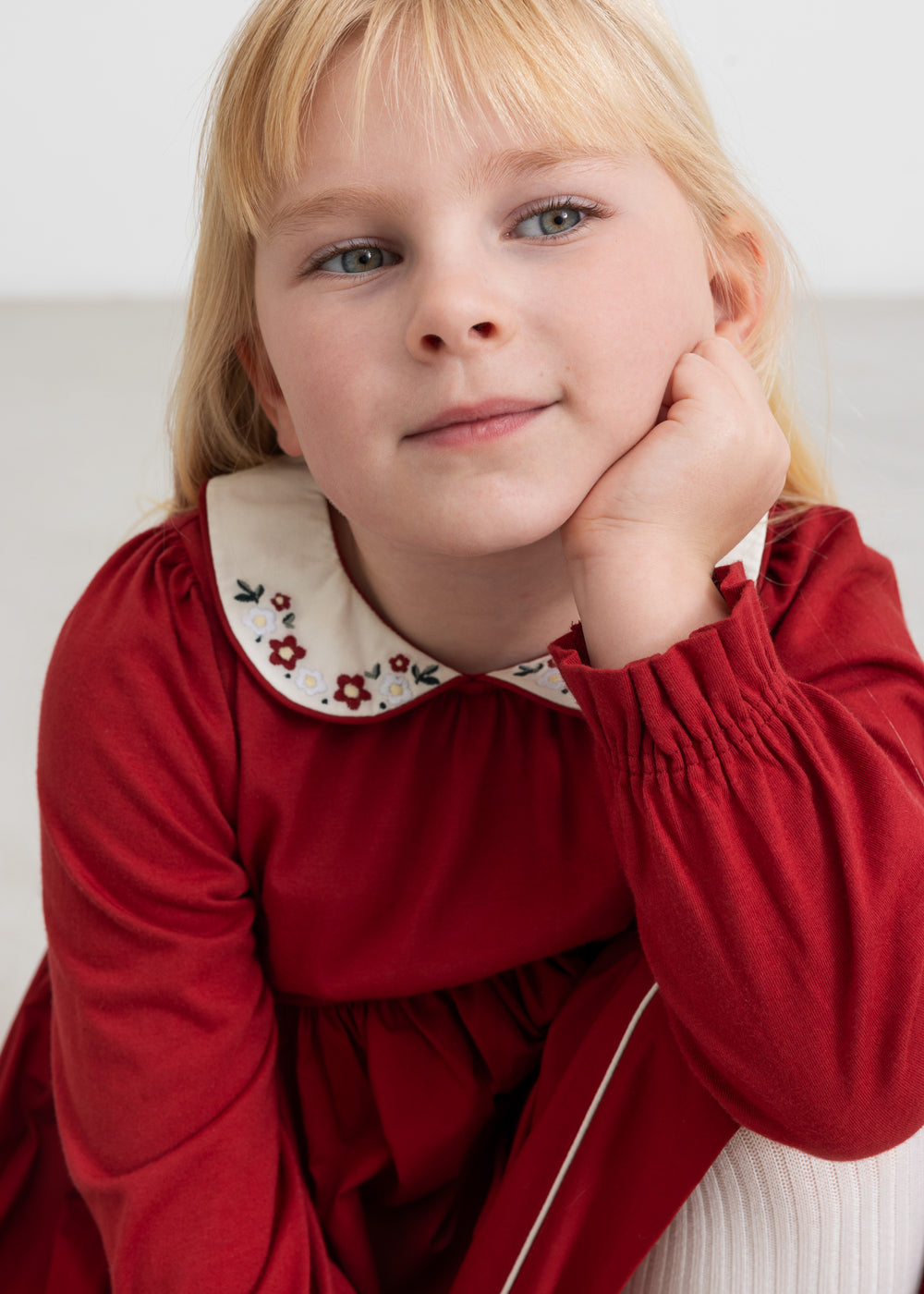 Pige iført rød julekjole med broderet krave i elegant festlook til børn