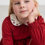 Pige iført rød julekjole med broderet krave i elegant festlook til børn