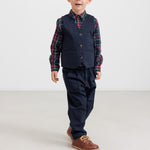 Dreng iført mørkeblå festbukser og vest med ternet skjorte i julelook til børn