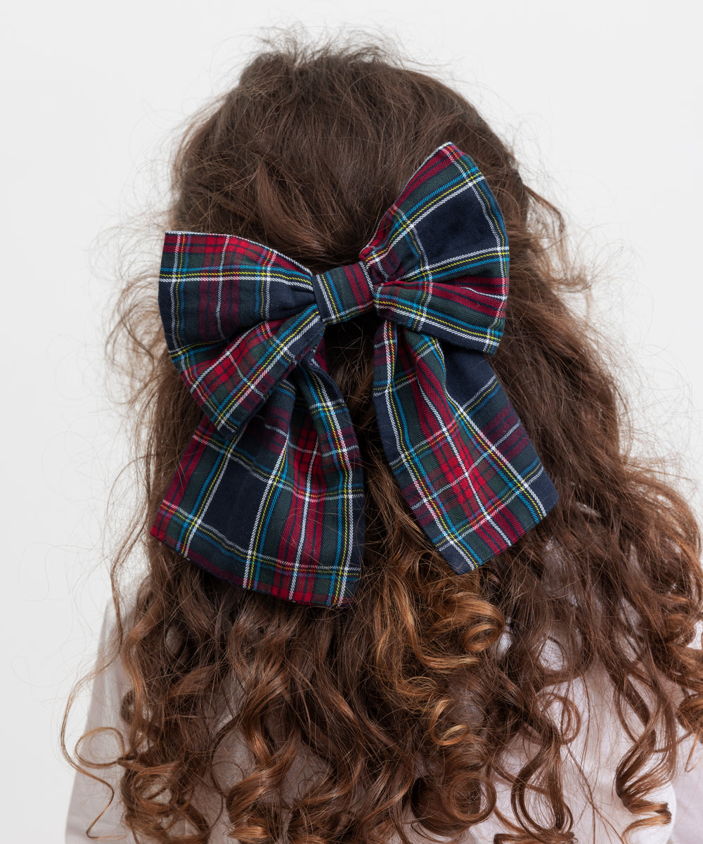 Pige med stort ternet sløjfspænde i håret i juleinspirerede mørkeblå, grøne og røde nuancer