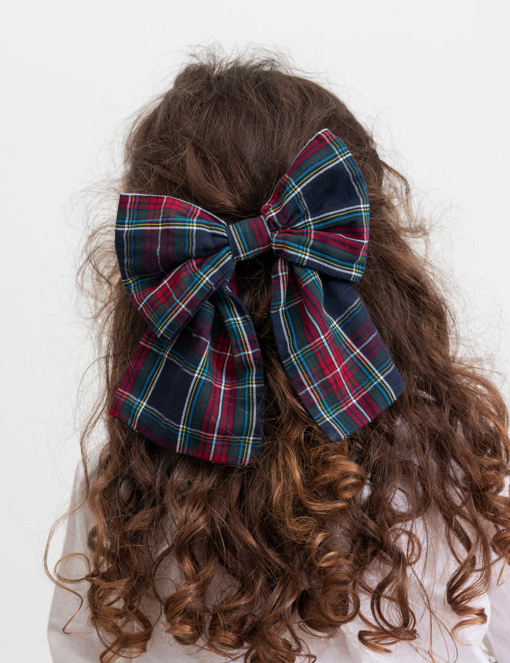 Pige med stort ternet sløjfspænde i håret i juleinspirerede mørkeblå, grøne og røde nuancer