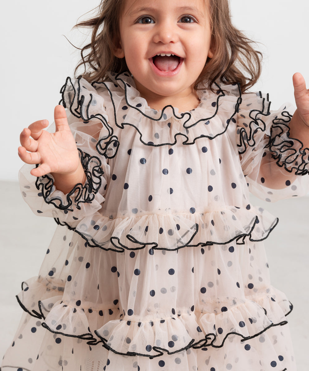 Baby iført lyserød julekjole i tyl med sorte prikker og flæser