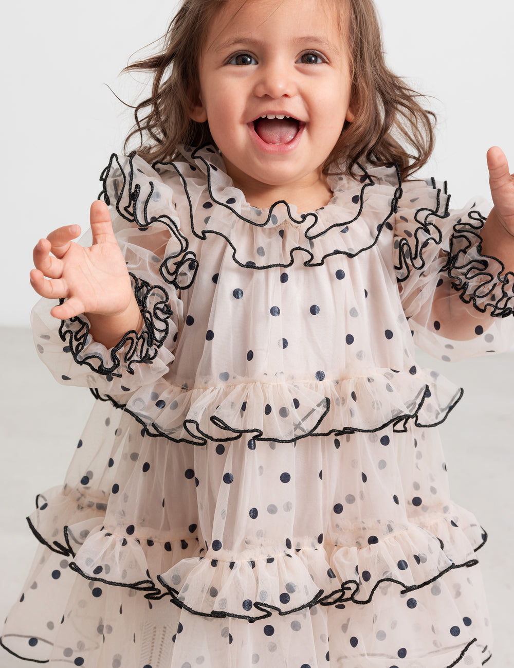 Baby wearing pink Christmas dress in tulle with black dots and ruffles