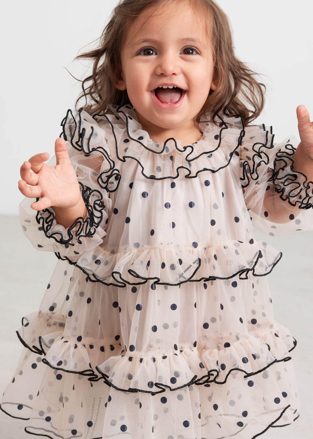 Baby iført lyserød julekjole i tyl med sorte prikker og flæser