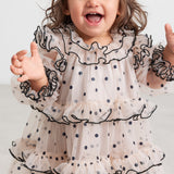 Baby iført lyserød julekjole i tyl med sorte prikker og flæser