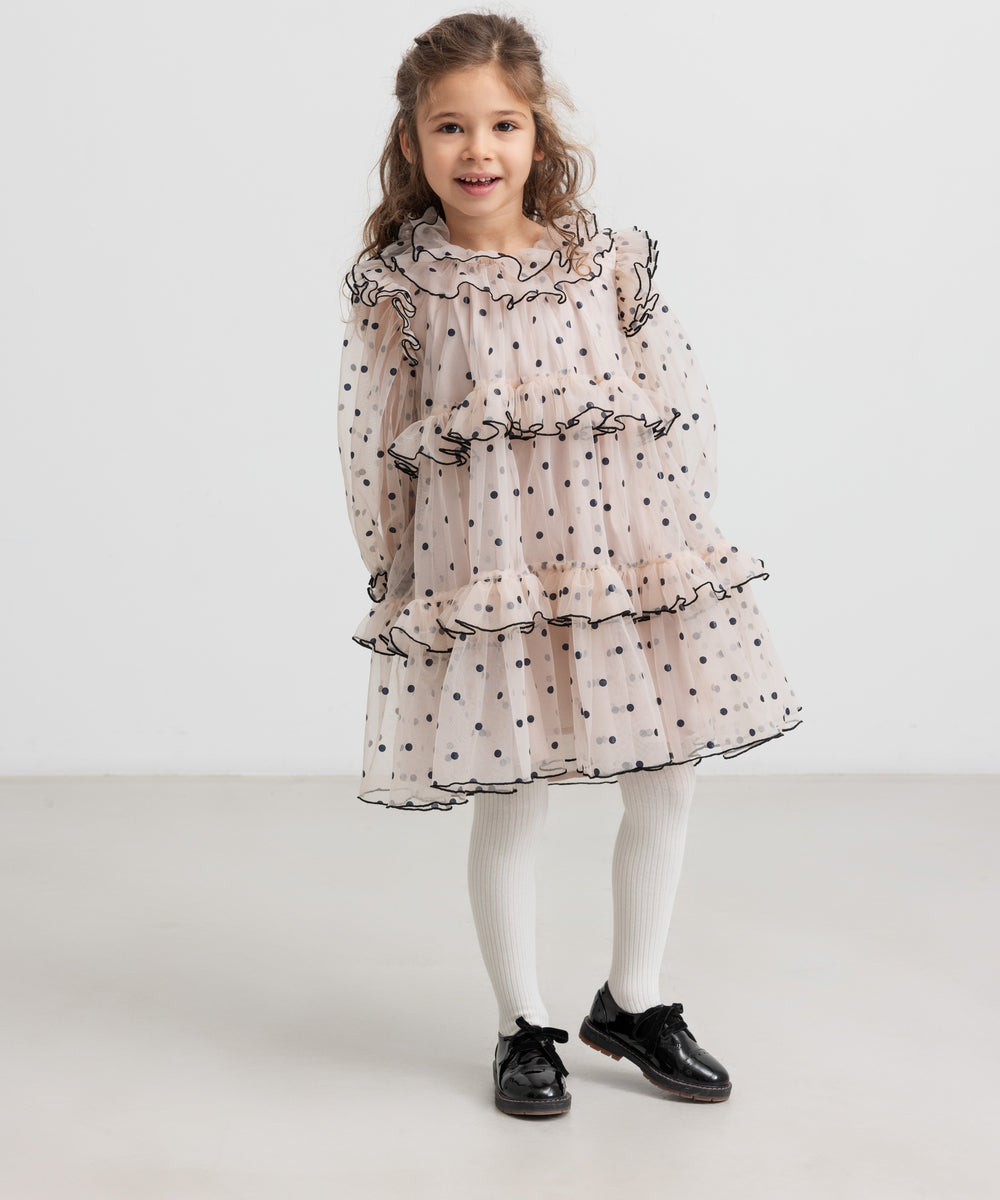 Pige iført lyserød julekjole med dots og cremefarvede strømpebukser til børn