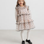 Pige iført lyserød julekjole med dots og cremefarvede strømpebukser til børn