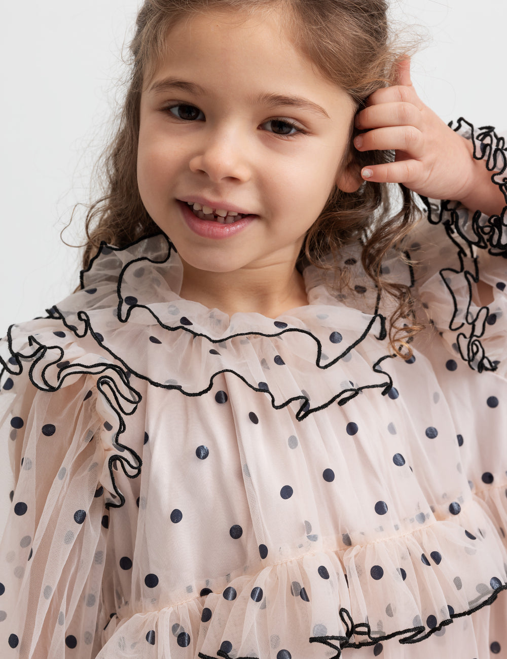 Pige iført lys beige julekjole i tyl med sorte prikker