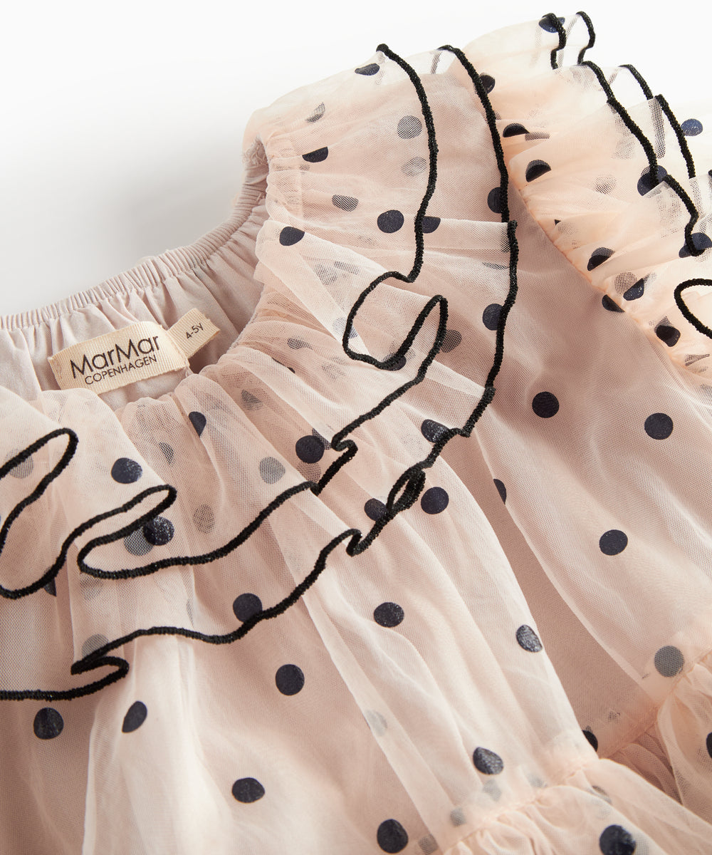 Nærbillede af krave med sorte flæser og prikker på lys beige julekjole i tyl til børn