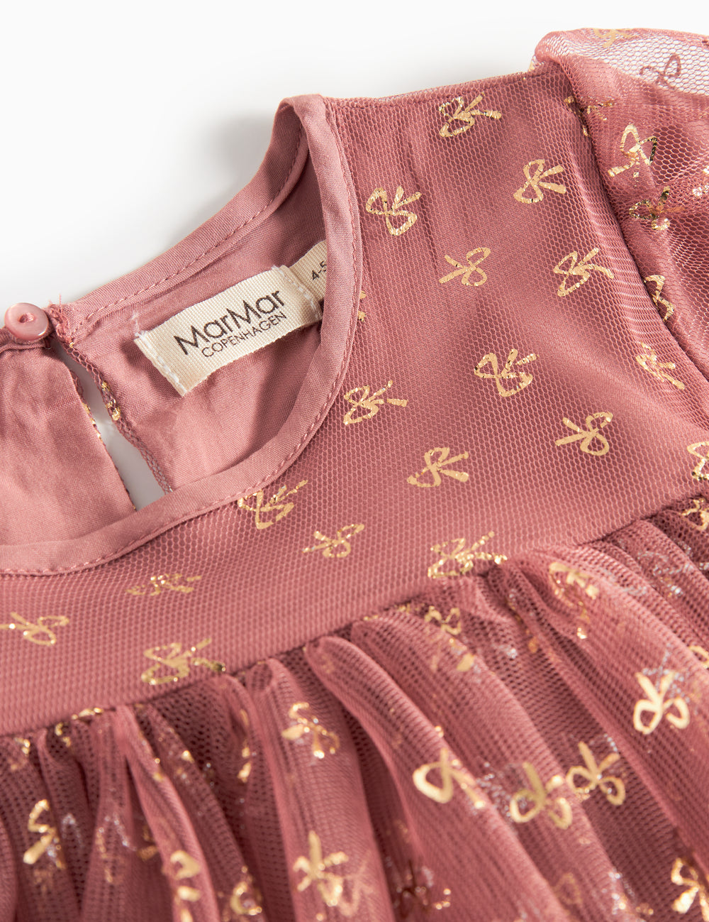 Nærbillede af overdel på rosa festkjole til børn i tyl med små gyldne mønstre