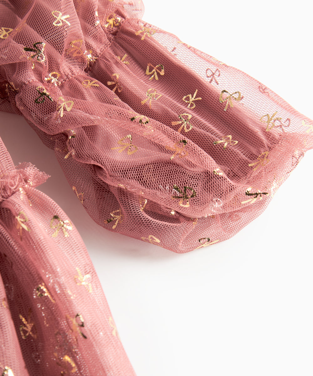 Nærbillede af overdel på rosa festkjole til børn i tyl med små gyldne mønstre