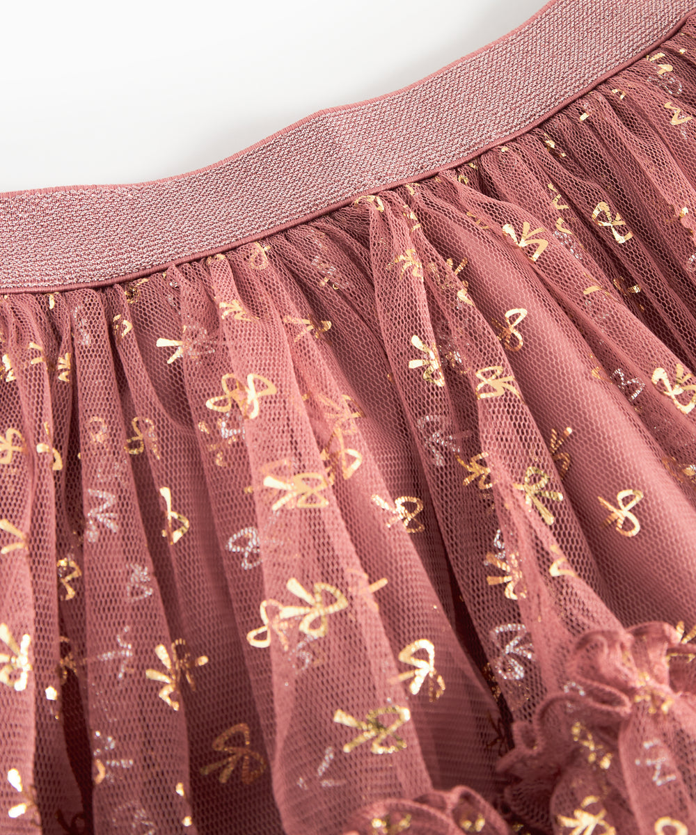 Detalje af tylstof på nederdel til børn med små gyldne prikker og flæser på rosa nederdel